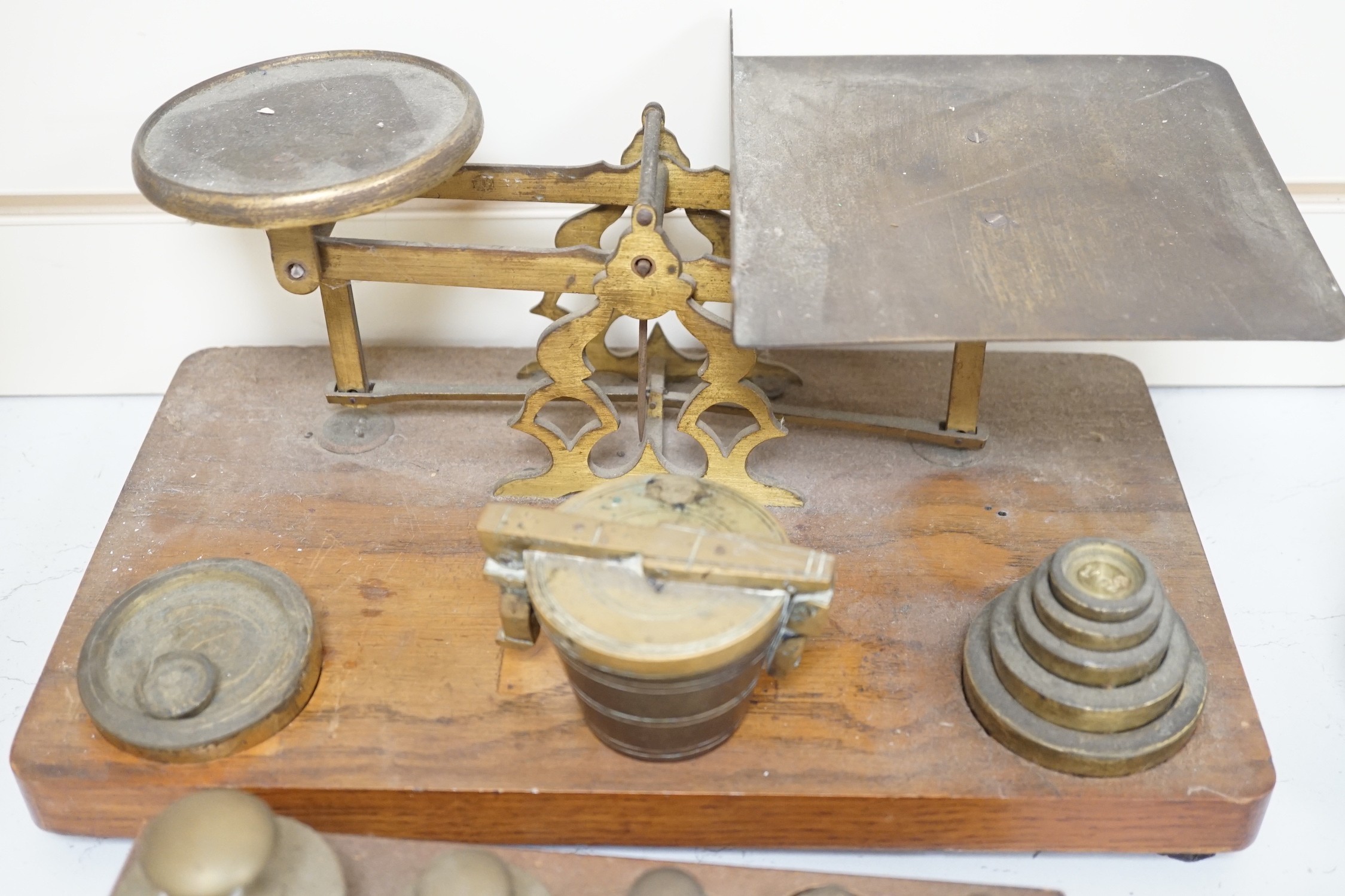 A set of brass postal scales and weights, a separate set of weights and another, set in wooden stand